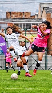 Intense action of women playing soccer on a green field.